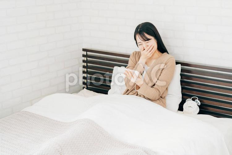 ベッドルームにいる女性（スマホを見る） スマホ,動画,映画の写真素材