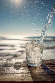 海を背景に注がれる清涼な氷水の写真