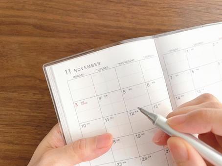 11月のスケジュール帳に記入する手元 スケジュール帳,書く,手の写真素材