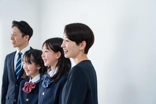スーツを着た男女と制服を着た女の子二人 入学式,父母,母親の写真素材