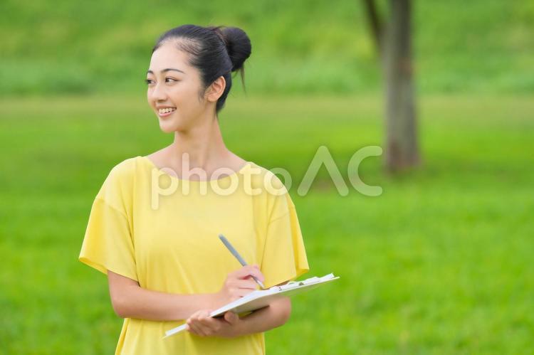 資料に記入しながら笑顔で遠くを見る女性 女性,インストラクター,資料の写真素材
