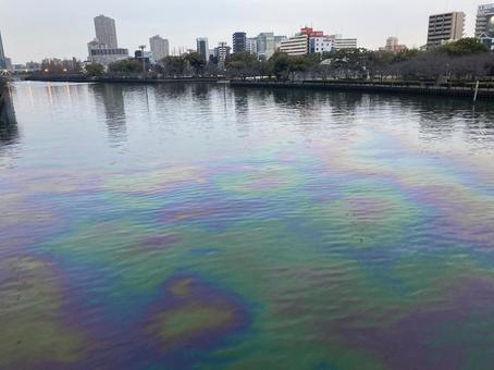 水面に浮かぶ油膜と都市の景色 水面に浮かぶ油膜と都市の景色の写真