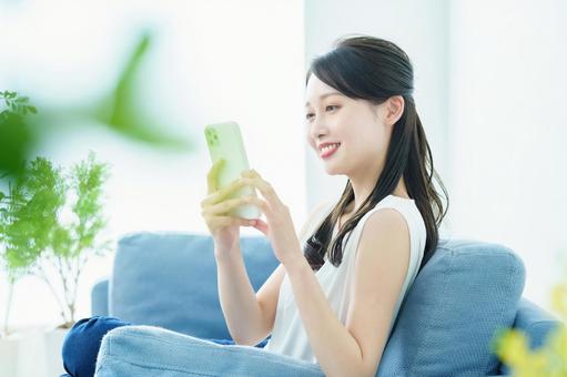 一個女人在沙發上操作智能手機, JPG 一個女人在沙發上操作智能手機, 女子, 智能手機, sns, JPG