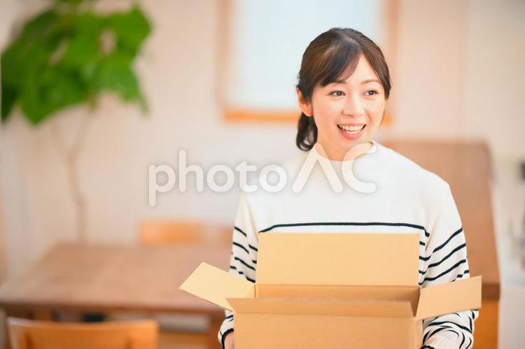 食卓で空いた段ボールを持ってよそ見をする女性 女性,主婦,空いたの写真素材