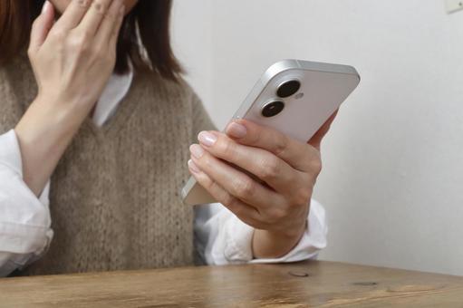 スマホを見て驚く女性 驚く,不安,動揺の写真素材