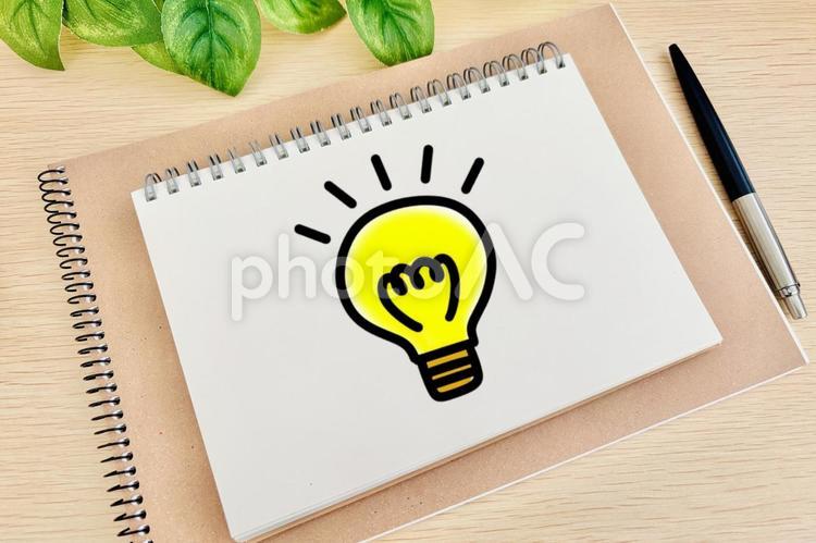 机の上に豆電球の絵が描かれたノート 豆電球,アイデア,ひらめきの写真素材