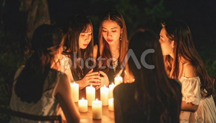 夜、ろうそくの火を囲んで怪談話をする若者 蝋燭,夏の夜,幽霊談の写真素材