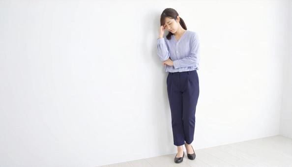 壁に寄りかかる落ち込んでいる日本人女性 壁に寄りかかる落ち込んでいる日本人女性の写真