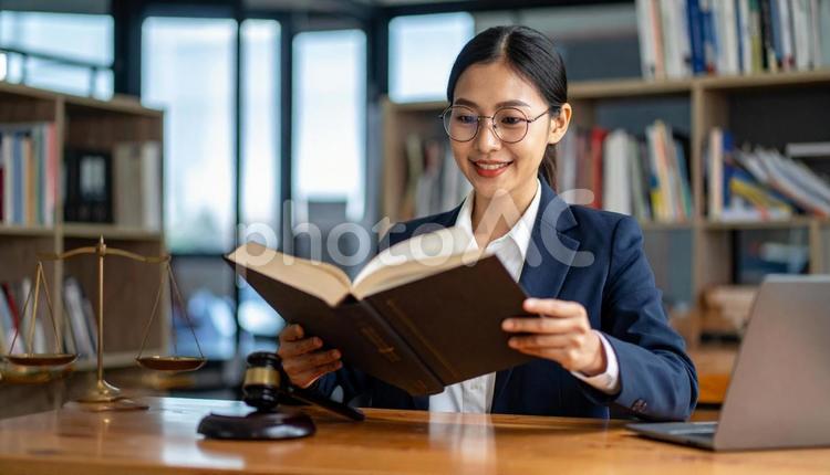 分厚い法律書を読む眼鏡の行政書士の女性 行政書士,本棚,女性の写真素材