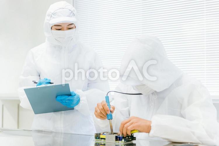 クリーンルームで精密機器を扱う男女 工場,ハンダ付け,ろう接の写真素材
