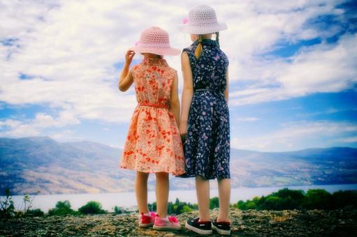 夏空の下で景色を眺める姉妹の後ろ姿 夏空の下で景色を眺める姉妹の後ろ姿の写真