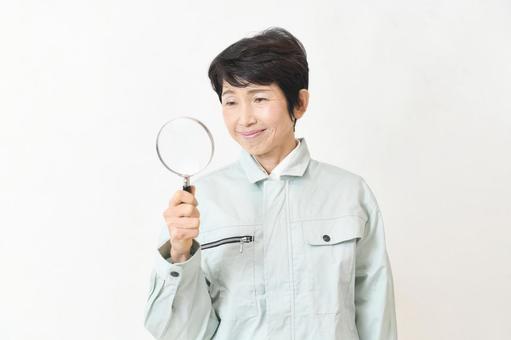 虫眼鏡を持ち調べる作業服姿のミドル女性 虫メガネ,作業員,虫眼鏡の写真素材