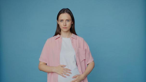 カメラ目線でお腹をさする女性 カメラ目線でお腹をさする女性 女性,人物,重ね着の写真素材