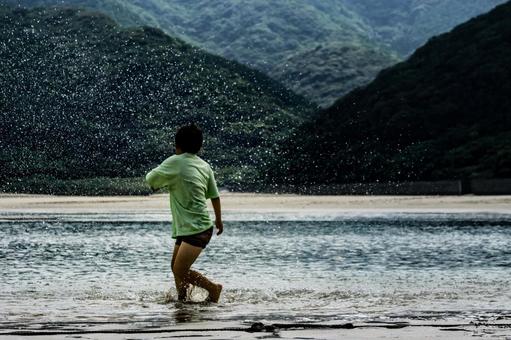 <素材>夕暮れの海で水遊びをする男の子 <素材>夕暮れの海で水遊びをする男の子の写真