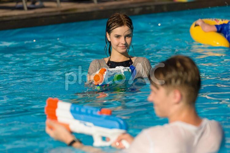 プールで水鉄砲で遊ぶティーンエイジャーの男女2 水鉄砲,男女,友達の写真素材