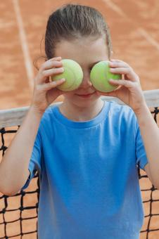 両手にテニスボールをもって目を隠す女の子 女の子,子供,外国人の写真素材