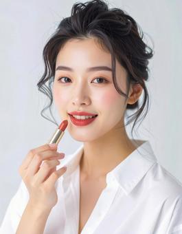 リップを塗る若い女性の美容ポートレートの写真