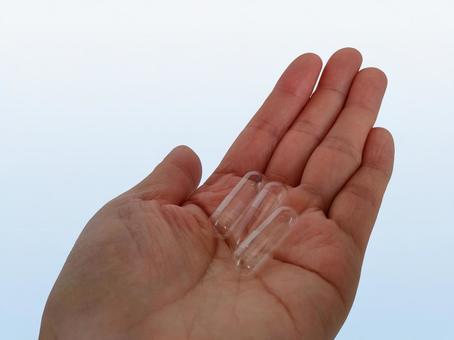 手のひらに載せた透明カプセル3個 薬,カプセル,カプセル錠の写真素材