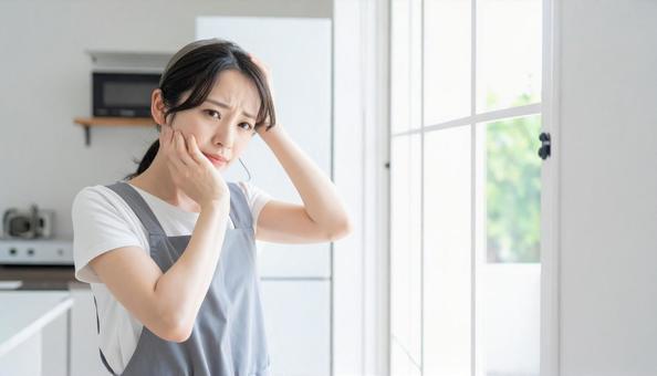 悩むエプロン姿の若い日本人女性 悩むエプロン姿の若い日本人女性の写真