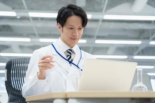 実験をする白衣の若い男性研究者 実験をする白衣の若い男性研究者の写真