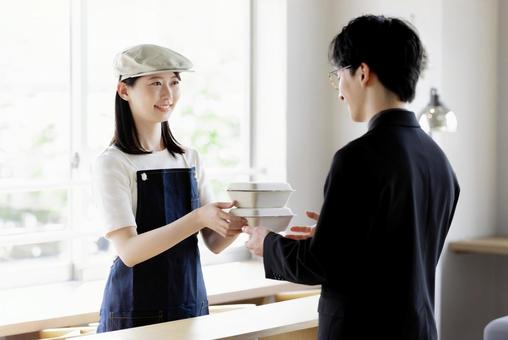 A store clerk handing out takeout items, JPG