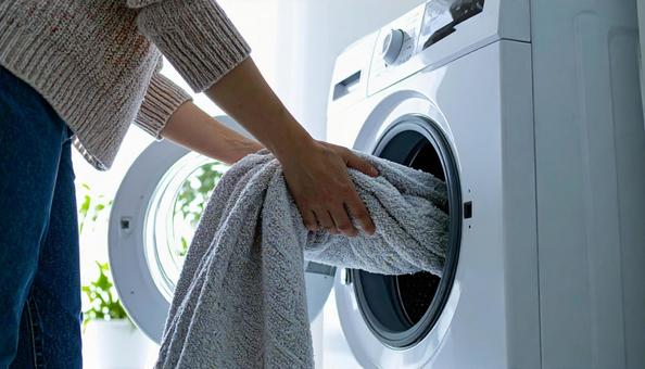 洗濯機から洗濯物を取り出す女性の手 洗濯機から洗濯物を取り出す女性の手の写真