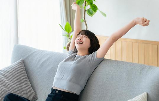 ソファで腕を伸ばしてリラックスする女性 ソファで腕を伸ばしてリラックスする女性 女性,リラックス,ストレッチの写真素材