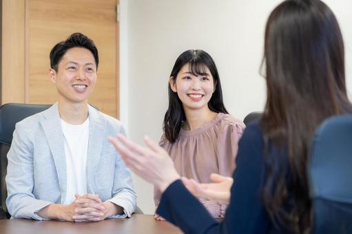 若い夫婦と商談をするセールスマン 若い夫婦と商談をするセールスマン セールスマン,会議,ビジネスの写真素材