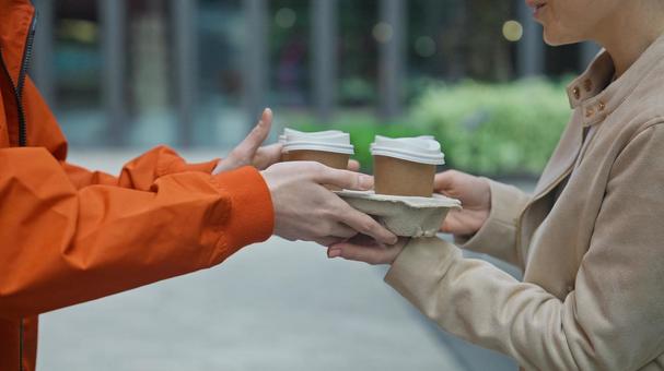 屋外でフードデリバリーの男性からドリンクを受け取る女性 配達,フードデリバリー,デリバリーの写真素材