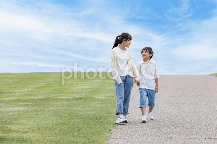 晴れた草原を笑顔で歩く子ども	 子ども,笑顔,歩くの写真素材