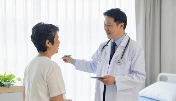 患者女性に説明する日本人医師 の写真