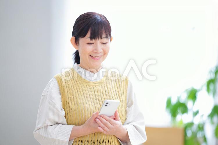 スマートフォンを見ながら微笑む女性 主婦,家政婦,シニアの写真素材
