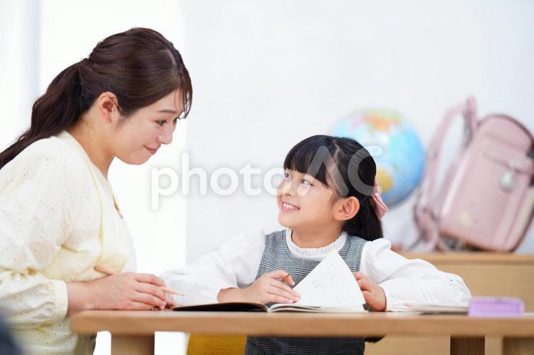 鉛筆を持ち笑顔で母を見る女の子 娘,母,笑顔の写真素材