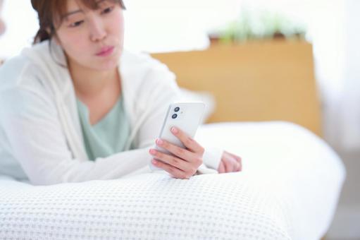 つまらなそうにスマホを見る女性 女性,スマートフォン,持つの写真素材