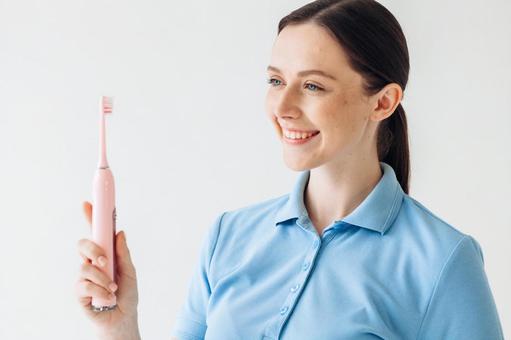 電動歯ブラシを持って説明する女性 電動歯ブラシを持って説明する女性の写真
