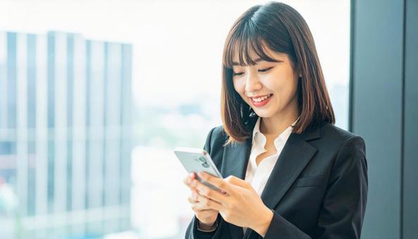 スマホを確認するビジネス女性 スマホを確認するビジネス女性の写真
