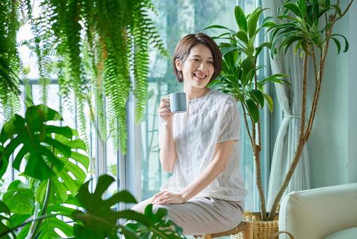 観葉植物に囲まれてリラックスする女性 観葉植物に囲まれてリラックスする女性 コーヒー,女性,ライフスタイルの写真素材