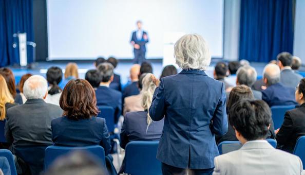 A back view of a shareholder asking a question to management at a shareholders' meeting, shareholder, businessman, microphone, JPG