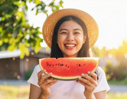 夏の屋外でスイカを持って笑顔を見せる女性の写真