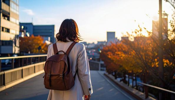 街中を歩いていくリュック姿の女性の後ろ姿 街中を歩いていくリュック姿の女性の後ろ姿の写真