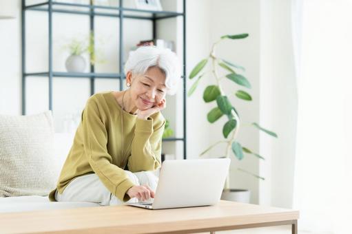 リビングでパソコンを使うシニアの女性 リビングでパソコンを使うシニアの女性 パソコン,シニア,高齢者の写真素材