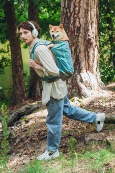 木の前で犬を背負う男性の写真