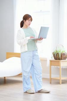 立ってパソコンを見ている女性の写真