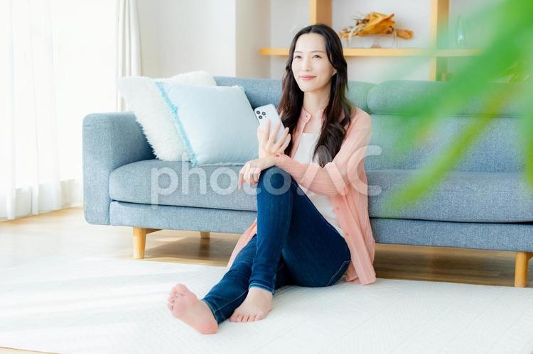 部屋でスマホを操作する女性 スマホ,笑顔,女性の写真素材