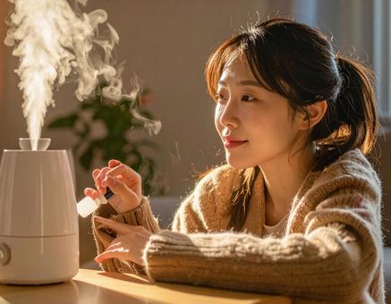 加湿器のそばでスキンケアをする女性 加湿器のそばでスキンケアをする女性の写真