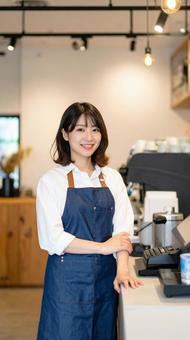カフェで女性バリスタが笑顔で接客する様子 カフェで女性バリスタが笑顔で接客する様子の写真