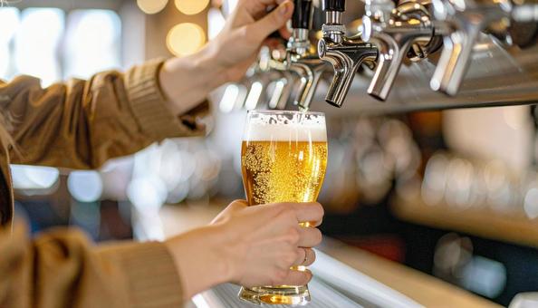 ビールサーバーでビールを注ぐ女性の手の写真