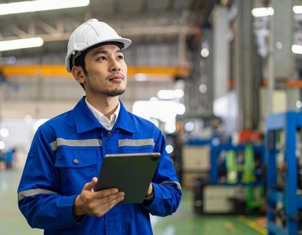工場内でタブレットで点検する作業員の男性 工場内でタブレットで点検する作業員の男性の写真