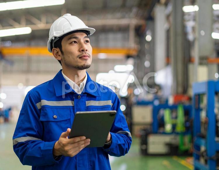 工場内でタブレットで点検する作業員の男性 工場,作業員,製造業の写真素材