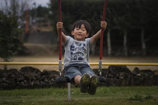＜素材＞秋の公園でブランコで遊ぶ男の子 子供,笑顔,ブランコの写真素材